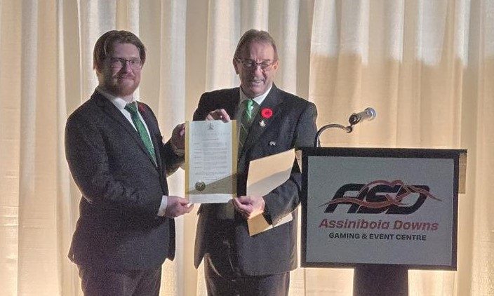 Minister signing the 4-H Month proclamation surrounded by 4-H members and leaders.